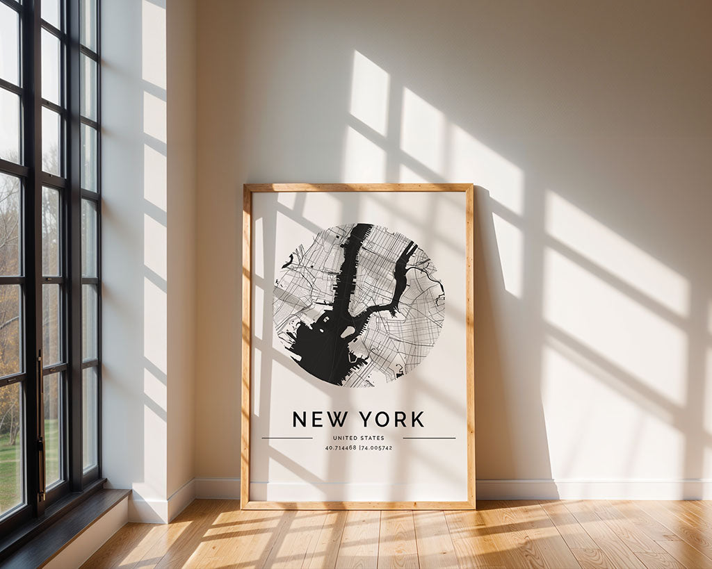 The FN Prints New York City Map, featuring a circular street and landmark design, rests against a light wall. Sunlight streams through large left windows, creating shadows on the floor and wall.