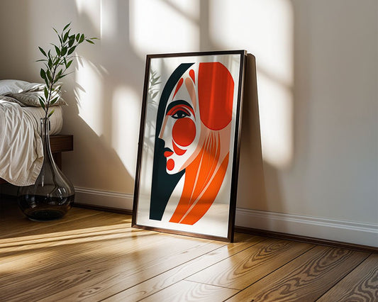 Abstract Allure by FN Prints is a framed minimalistic artwork with bold red, black, and beige shapes. It leans against a wall on a wooden floor as sunlight highlights the piece and a glass vase with green foliage nearby.