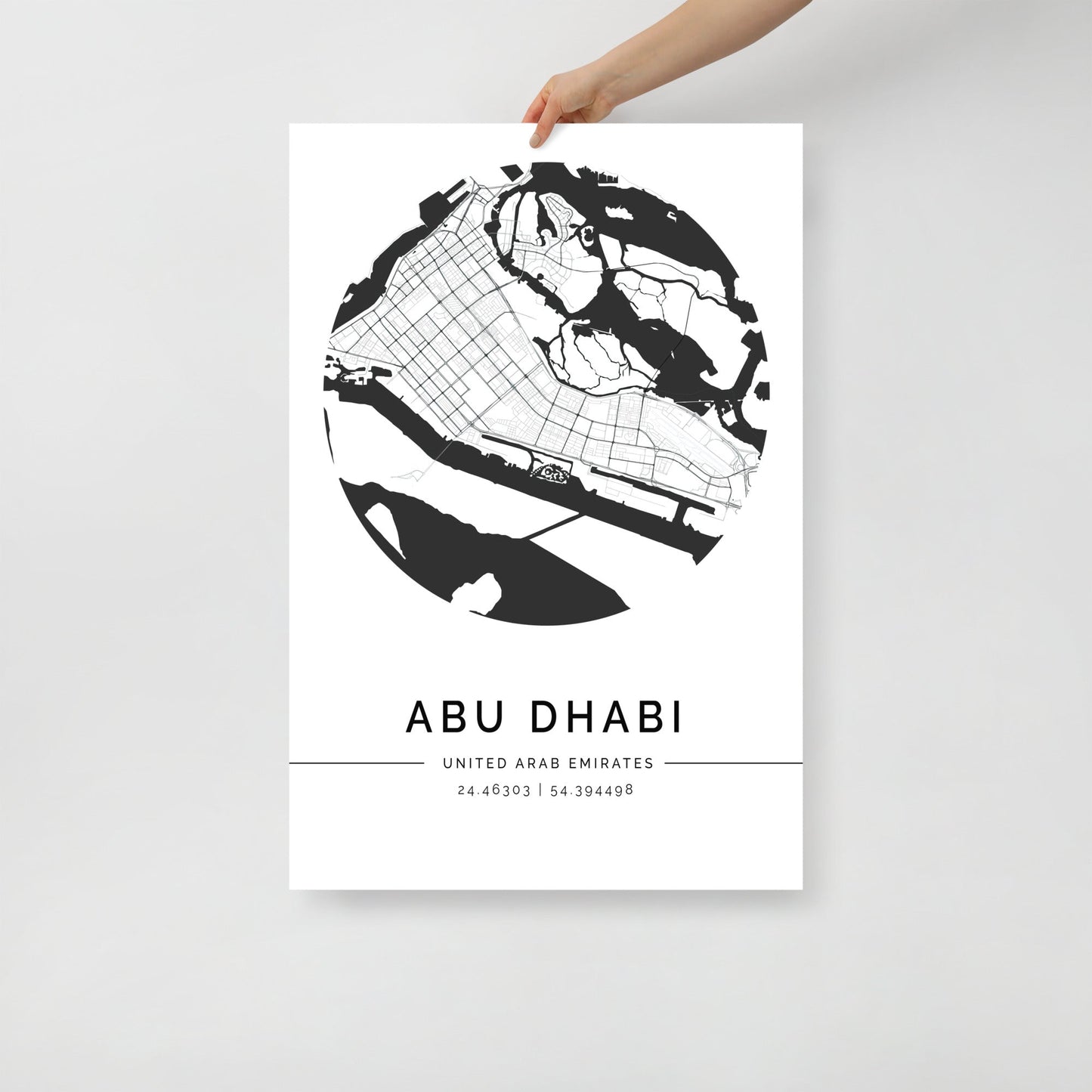 A black and white minimalist print of Abu Dhabi city map, held up against a white background