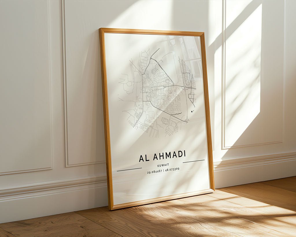 An "Al Ahmadi City Map" by FN Prints, printed on museum-quality fine art paper, leans against a white paneled wall. The map features coordinates and sunlight casts patterns across the minimalist print and wooden floor.