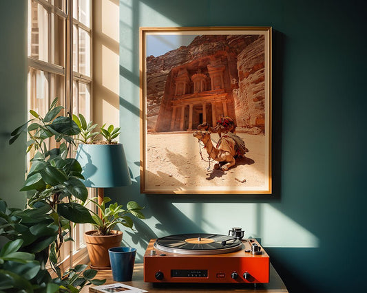 A sunlit room with green walls displays FN Prints’ "Al-Khazneh - The Treasury - Petra: Part I" framed photo, a camel, potted plants, and an orange turntable spinning vinyl on a wooden table by a large window.