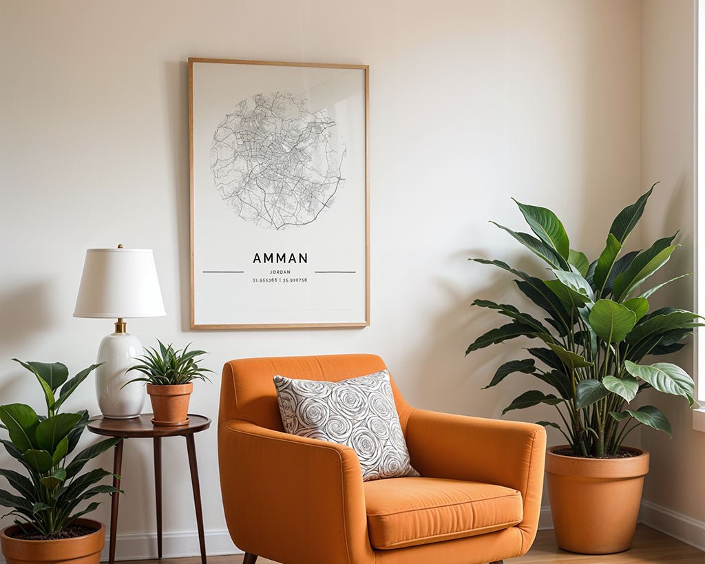 A cozy corner features an orange armchair with a patterned cushion, a small round table with a lamp and potted plants, and FN Prints' Amman City Map on museum-quality fine art paper above, adding character as natural light filters in.