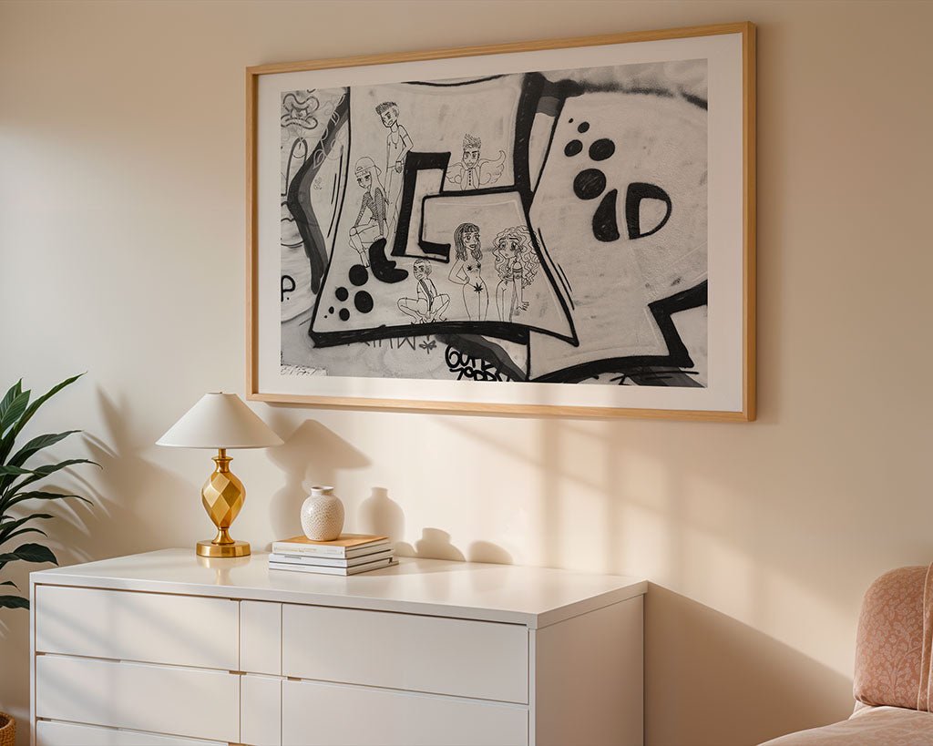 A modern bedroom features a white dresser with a gold lamp, plant, and books. Above sits FN Prints' "Anime Graffiti Fusion," a large abstract black-and-white artwork in a light wood frame. Sunlight casts shadows on the wall and furniture.