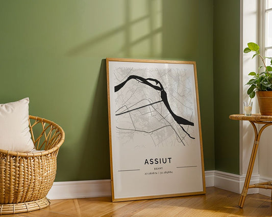 A framed FN Prints Assiut City Map adorns the green wall, depicting Egypt’s oldest city in detail on museum-quality paper. A wicker chair with a white cushion is nearby, next to a round table with a potted plant enjoying sunlight by the window.