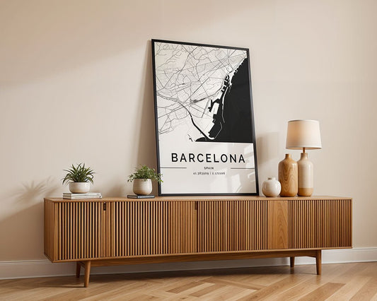 A mid-century modern sideboard with vertical grooves supports an FN Prints Barcelona City Map poster, ideal for urban design lovers. It's adorned with two potted plants, a lamp, and a ceramic vase. The light wood floor and neutral walls beautifully highlight the wall art.