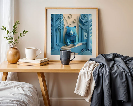 A wooden table with two mugs and a stack of books sits under the whimsical FN Prints digital artwork titled "Bazul The Bear," featuring a blue bear in a forest. A draped gray and white cloth adds texture, while a vase with green branches enhances the charming scene.