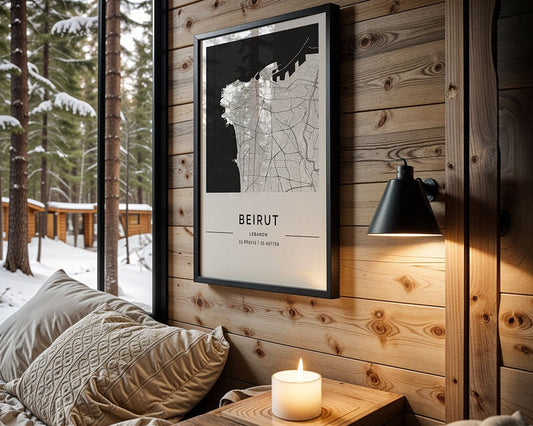 A minimalist FN Prints Beirut City Map on museum-quality art paper hangs in a cozy cabin. A black lamp lights it above a bed with beige pillows and blankets. A candle sits on the windowsill, with snow-covered trees visible outside.