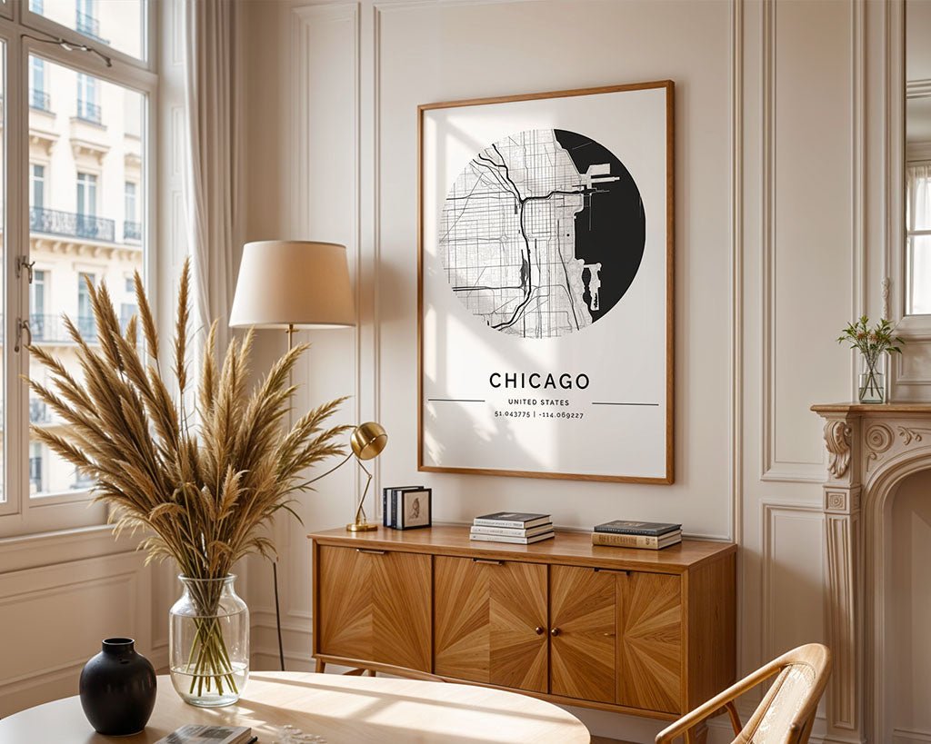 A stylish room showcases an FN Prints Chicago City Map on the wall above a geometric wooden sideboard. The sideboard displays a lamp, small decor, and a vase of dried pampas grass. Large windows let natural light enhance the space's minimalist charm.