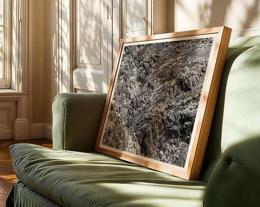 A framed "Delicate Waterfall" black and white print by FN Prints sits on a green upholstered sofa in a bright room with white paneled walls and wood floors.