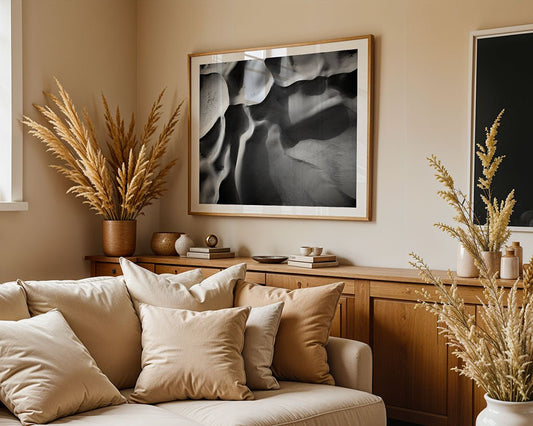 A beige living room features a light sofa with cushions, wooden sideboard, dried pampas grass, and "Dune Part II" wall art by FN Prints above the sideboard. Natural light from a window enhances the calm, desert-inspired decor.