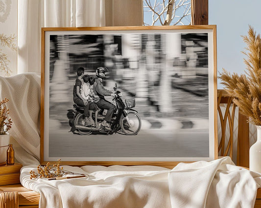 The "Family Journey" black and white framed photo by FN Prints sits on a beige fabric-draped table, accented by decorative plants, a window, and neutral furnishings.