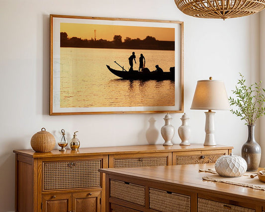 The "Golden Fishermen" framed print by FN Prints hangs above a wooden sideboard with vases and a table lamp, adding warmth to a cream-colored dining room.