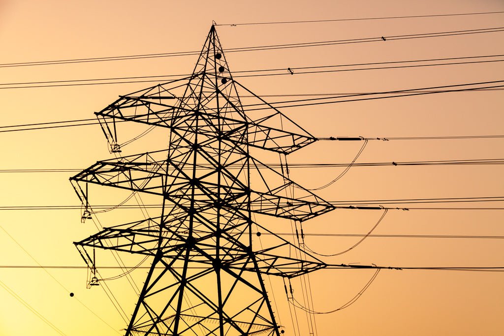 High voltage power lines tower silhouette in Dubai at sunset
