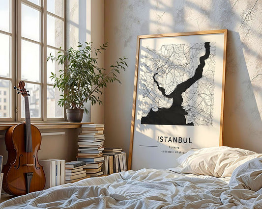 A sunlit bedroom showcases an FN Prints Istanbul City Map leaning against the wall, enhancing the bright space. Nearby, a violin sits beside a stack of books by a window with a leafy plant. The unmade bed is partially visible in the soft natural light.