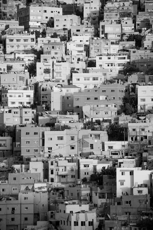 FN Prints' Jabal Amman Black & White showcases a densely packed urban neighborhood in Jabal Amman, highlighting numerous multi-story residential buildings closely situated on a hillside. The structures, varying in shape and size, are constructed with a blend of concrete and brick materials.