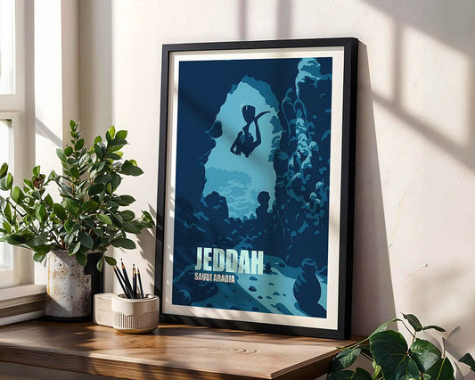 Framed poster of 'Jeddah, Saudi Arabia' on a wooden shelf with plants.