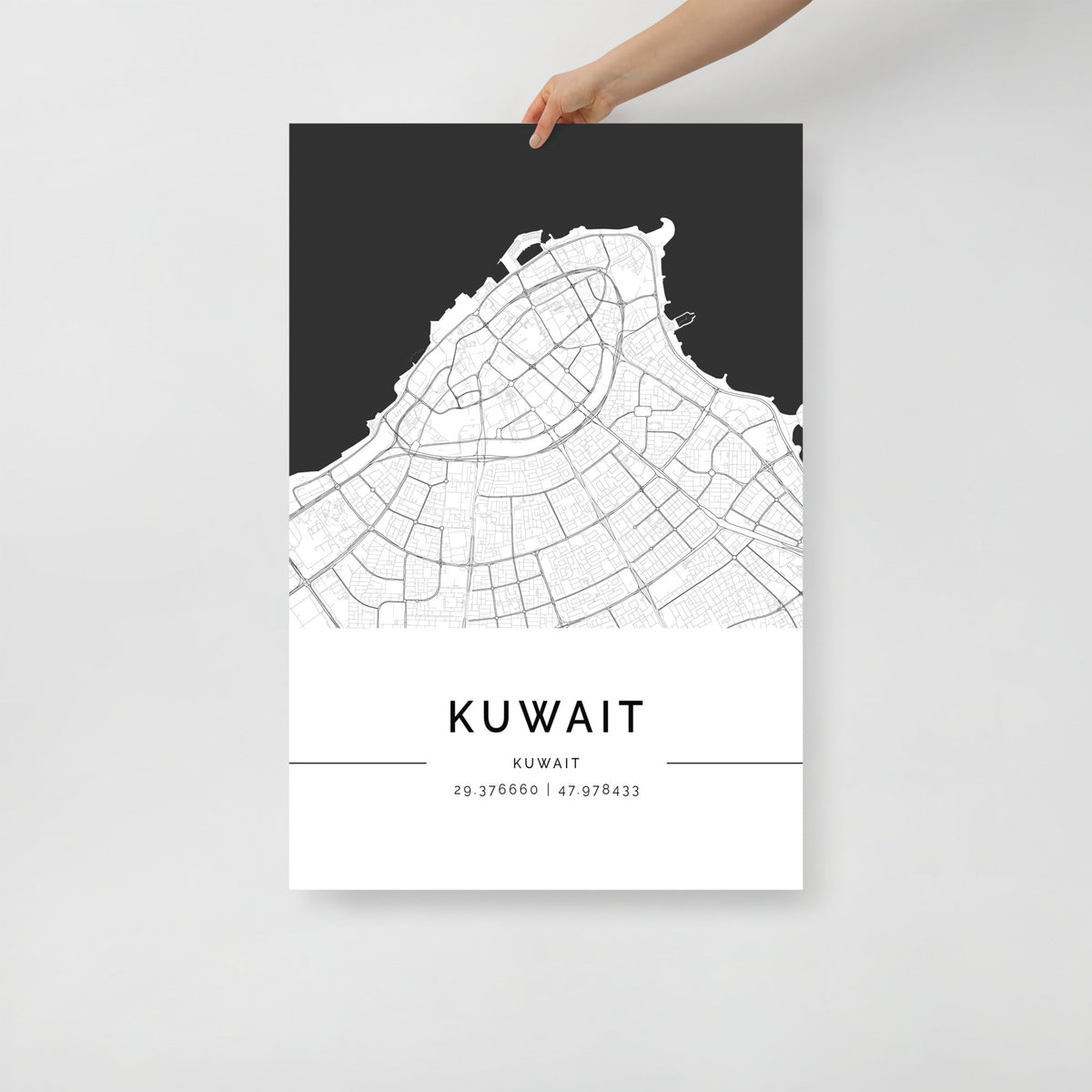 A hand holding a black and white map poster of Kuwait City.