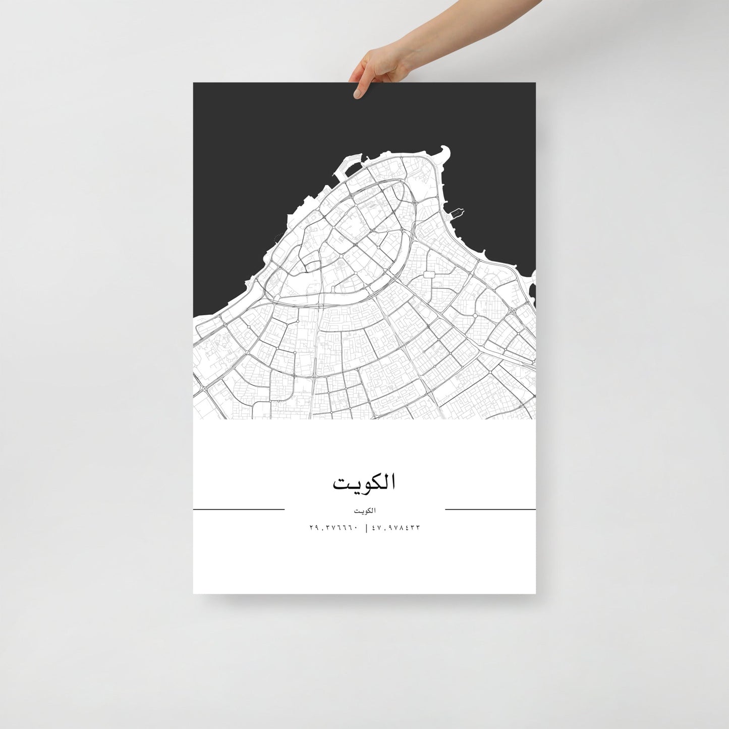 A hand holding a black and white map poster of Kuwait City.
