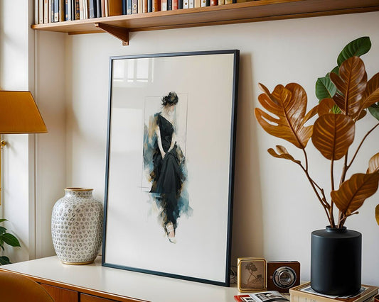 Lady in Black by FN Prints, a framed abstract of a seated woman in a black dress, is displayed on a wooden desk alongside a large ceramic vase, potted plant, and decor items, with a bookshelf above.