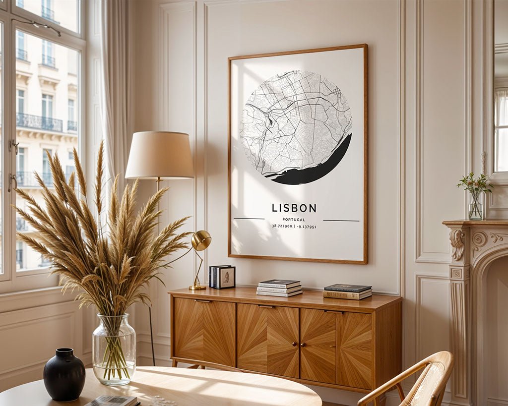 A stylish sunlit room features FN Prints' Lisbon City Map poster as wall art, a modern wooden sideboard with decor items, a large vase of dried grasses, a table lamp, and elegant molding. Tall windows enhance the European cities decor by filling the space with natural light.