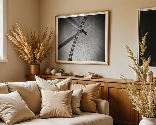 A beige living room with a cream sofa, neutral pillows, and dried plants in vases. A sideboard displays decor, while FN Prints’ “London Eye” wall art hangs above. Natural light streams in from a window.