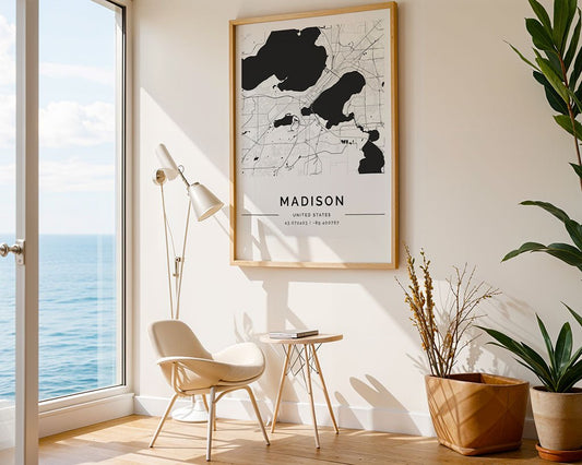 A bright room with a large window overlooking the sea includes a white chair and a small wooden table next to a standing lamp. Greenery is added by a potted plant, while FN Prints' Madison City Map in museum-quality paper adorns the wall as framed city wall art.