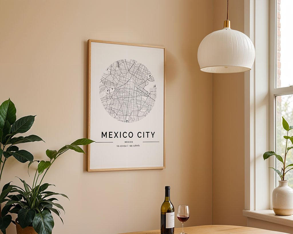 A framed FN Prints Mexico City Map on fine art paper is displayed on a beige wall. Below, a round wooden table holds a wine bottle and glass, with a plant at the edge. A white dome pendant light adds to the minimalist setting.