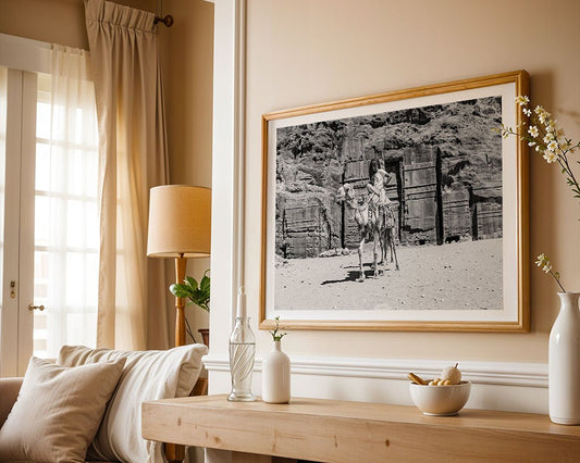 A neutral-toned living room with a wooden console table, white vases, and the "Modern Bedouin" framed photograph by FN Prints featuring a person riding a camel in a desert scene on the wall.