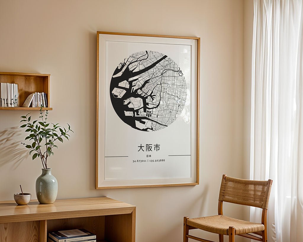 A minimalist room with light walls is decorated with the FN Prints Osaka City Map, a striking wall art piece, alongside a wooden shelf holding books and greenery, a wooden table, and a woven chair beside airy white curtains.