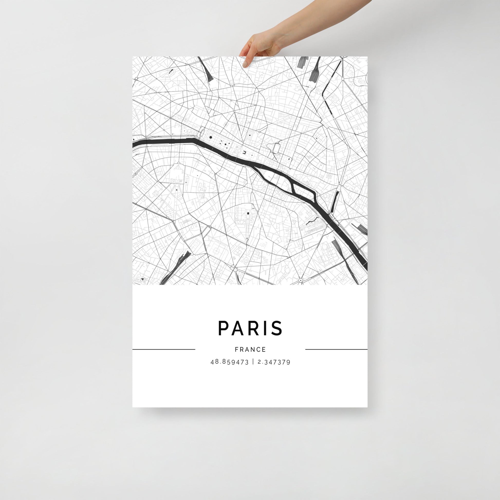 A minimalist black and white map poster of Paris, France, held up against a white background.