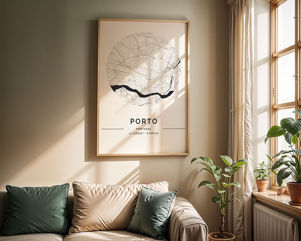 A beige sofa with green and beige cushions sits in the living room. A museum-quality FN Prints Porto City Map hangs on the wall, while sunlight fills the room, illuminating potted plants on the windowsill and floor.