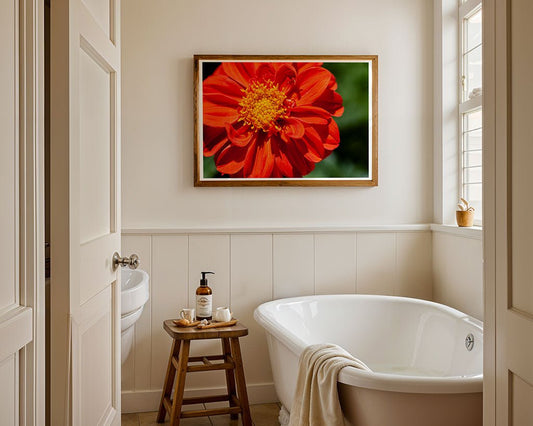 A bright bathroom features a white bathtub, a wooden stool with a soap dispenser and towel, and FN Prints’ "Red Dhalia (Dahlia Coccinea)" floral wall art above the tub. Natural light pours in through the window.