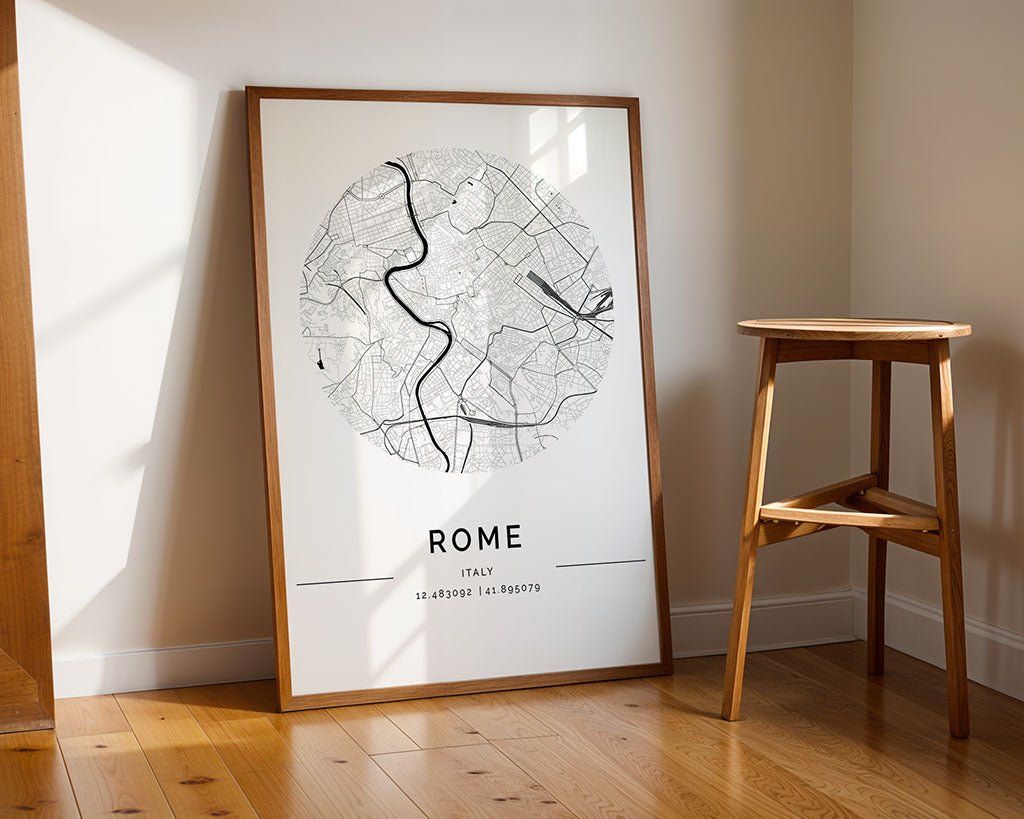 The FN Prints Rome City Map, a high-quality framed print, is displayed on the floor beside a wooden stool. Sunlight graces the wall and hardwood floor, casting shadows that enhance this minimalist piece in the room's cozy corner.