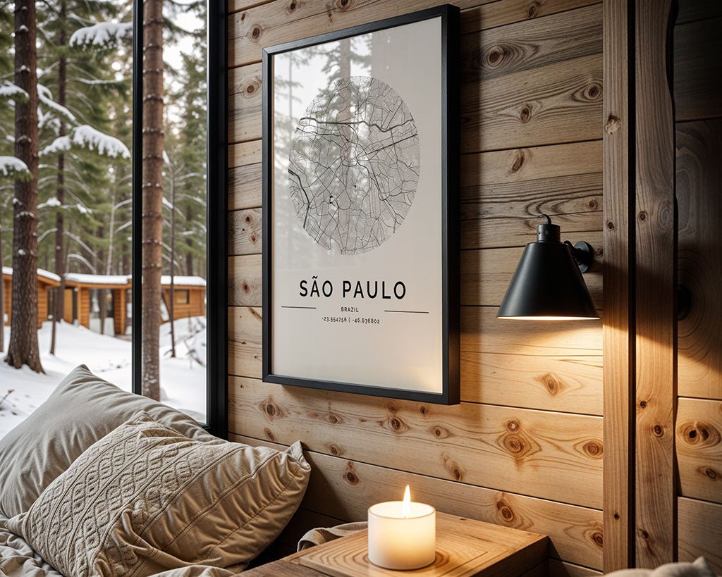 A cozy cabin's interior showcases FN Prints' São Paulo City Map as stunning wall art on a wooden wall. A lit candle on a small table below the map highlights modern minimalism, while through the window, snowy forests reveal warmly nestled wooden cabins outside.