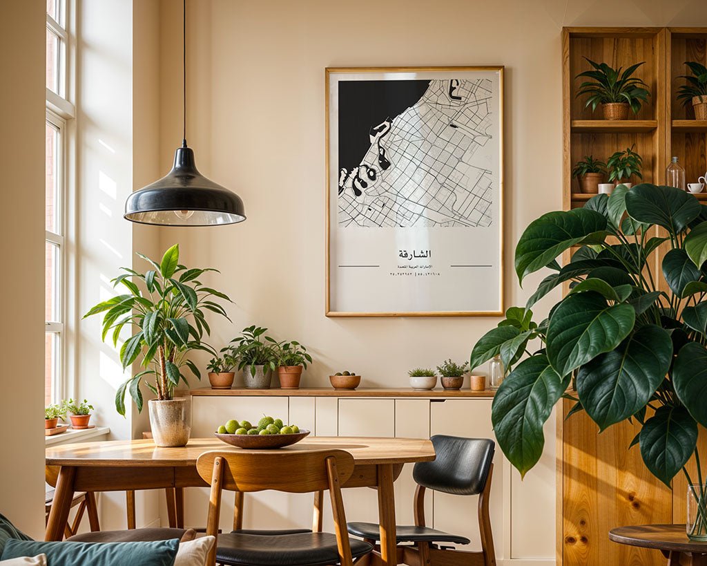 A dining area with wooden furniture, potted plants, a bowl of green apples, and a minimalist FN Prints Sharjah City Map on the wall with Arabic text, all illuminated by natural light from large windows.