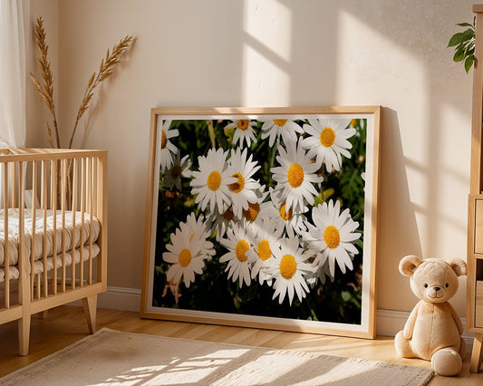 An FN Prints framed photo of Shasta daisies (Leucanthemum × Superbum), featuring yellow centers, leans against a light wall near a wooden crib and beige teddy, adding soothing artwork to the sunlit room decorated with dried plants for natural ambiance.