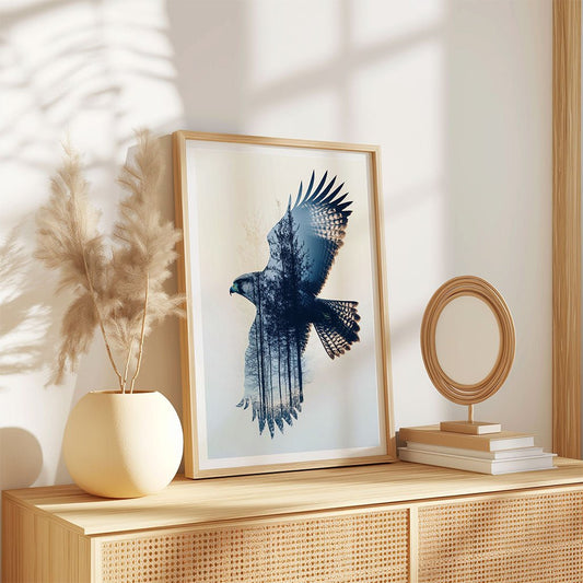 Silent Flight by FN Prints, a nature-inspired framed wall art with a hawk and forest scene, leans on a wooden console. A round mirror, stacked books, and pampas grass complete the calming decor.