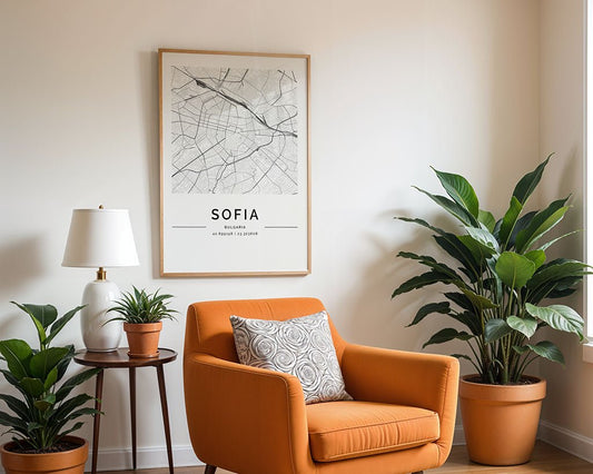 A cozy room corner features an orange armchair with a patterned pillow, a small side table adorned with a white lamp, and potted plants. A FN Prints Sofia City Map enlivens the wall, while two large green potted plants enhance the inviting decor.