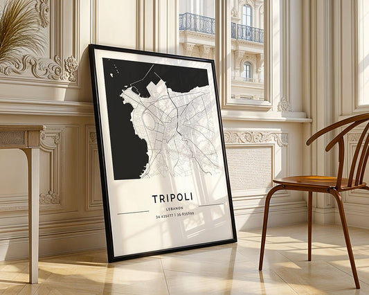 A Tripoli City Map by FN Prints, printed on museum-quality fine art paper, leans elegantly against a sunlit room's paneled wall. A wooden chair adds charm nearby. The minimalist print meticulously displays the coordinates 34° 26' 31" N, 35° 50' 39" E at the bottom.