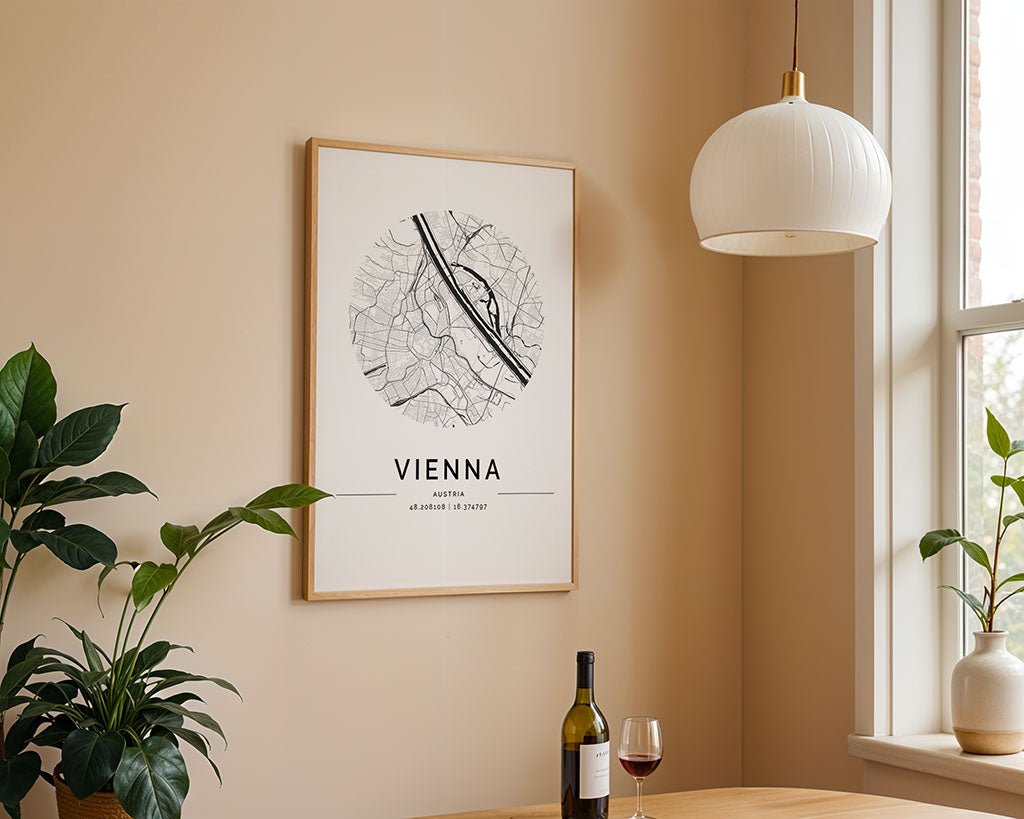 In a minimalist room with beige walls, an FN Prints Vienna City Map hangs above the table. On the table are a wine bottle, glass, and green plant. A white pendant light from the ceiling softly illuminates this elegant setting and the Austria city map.