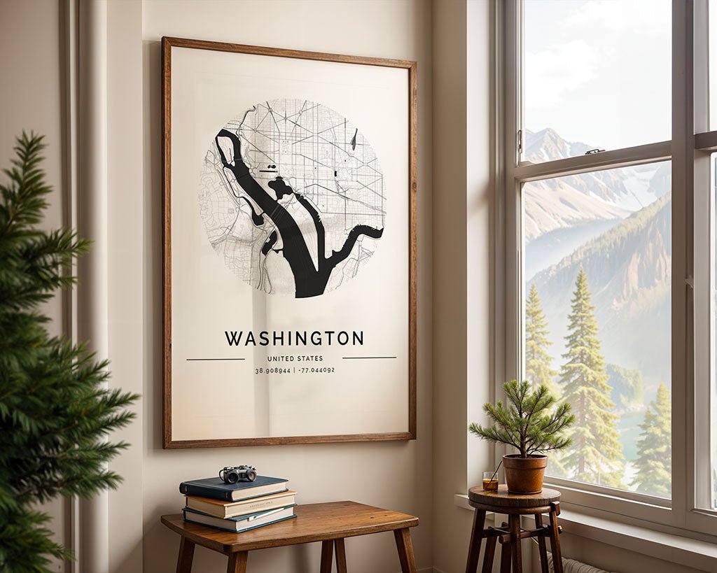 The FN Prints Washington City Map hangs on a beige wall beside a window with mountain views. Below, a table holds books, a camera, and a plant—ideal minimalist decor for any space.