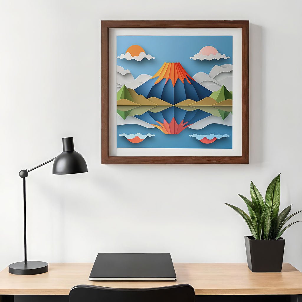 A minimalistic desk setup includes a black lamp, a closed laptop, and a potted plant. Above the desk is "2 Suns Volcano," a colorful, framed landscape artwork by FN Prints, showcasing mountains and clouds in a folded paper effect that evokes stunning digital art.