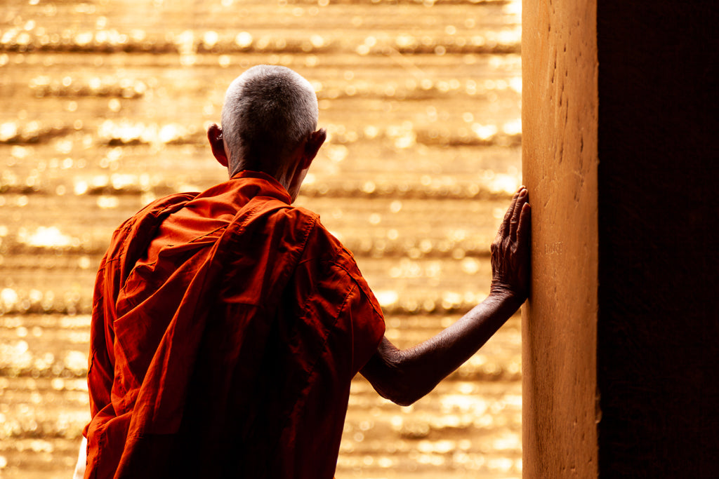 A monk leaning on a wall with a golden background in Angkor Wat at siem reap in Cambodia. 