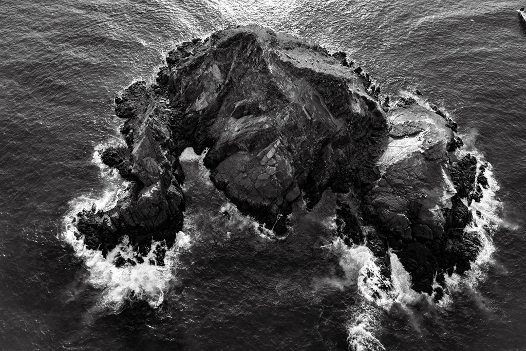 FN Prints' exquisite artwork, "Snoopy Island Black & White," is a captivating black and white aerial photograph that captures the rugged terrain and steep cliffs of a rocky island. Surrounded by crashing ocean waves, this piece perfectly encapsulates the coastal charm of Snoopy Island.