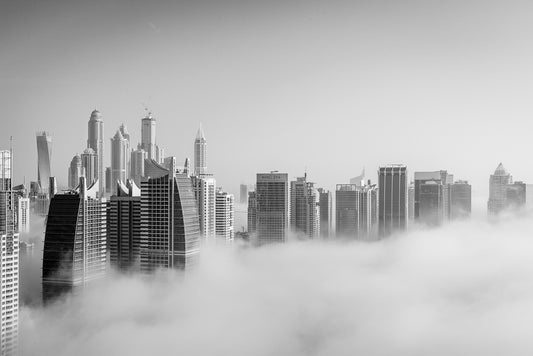 Jumeirah Lake Towers in the morning with fog covering the area and the towers peaking above the clouds. 