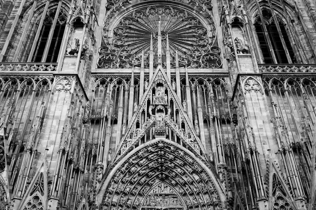 Black and white photograph of FN Prints' Cathédrale Notre-Dame de Strasbourg's ornate Gothic facade, featuring intricate stone carvings, tall spires, and a large circular stained glass window. This architectural masterpiece showcases pointed arches, elaborate sculptures, and geometric patterns.