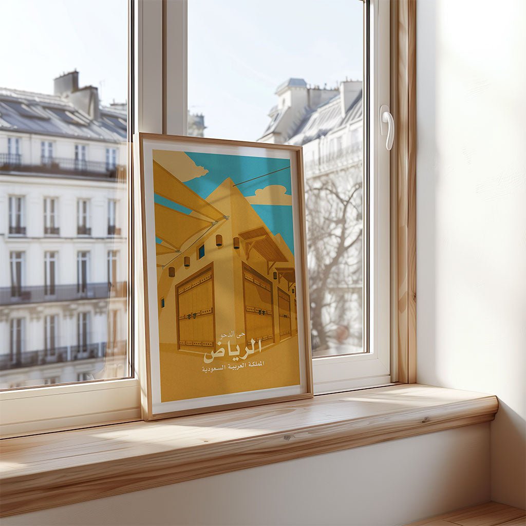 Framed artwork on a windowsill with a cityscape reflection in the window.