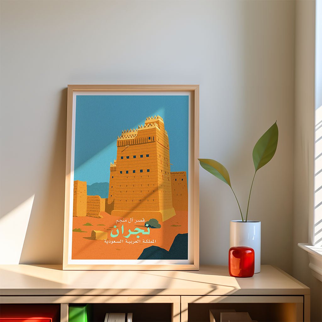 Framed poster of Al Mahran Palace in Najran, Saudi Arabia, on a shelf with decor items.