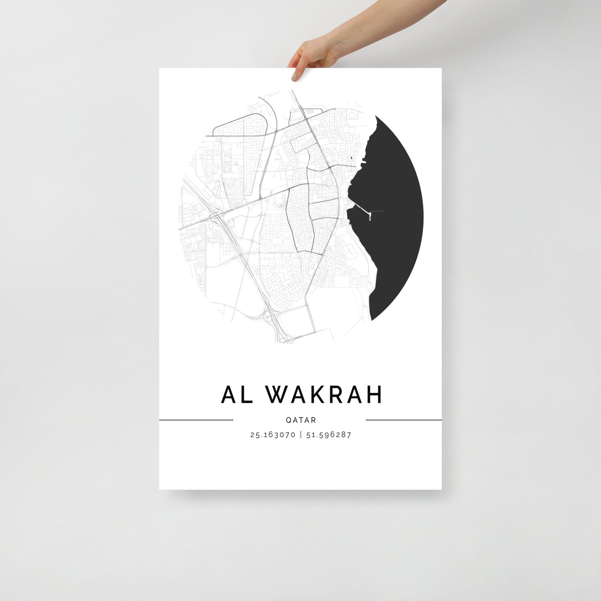 Map poster of Al Wakrah, Qatar held by a hand on a light gray background