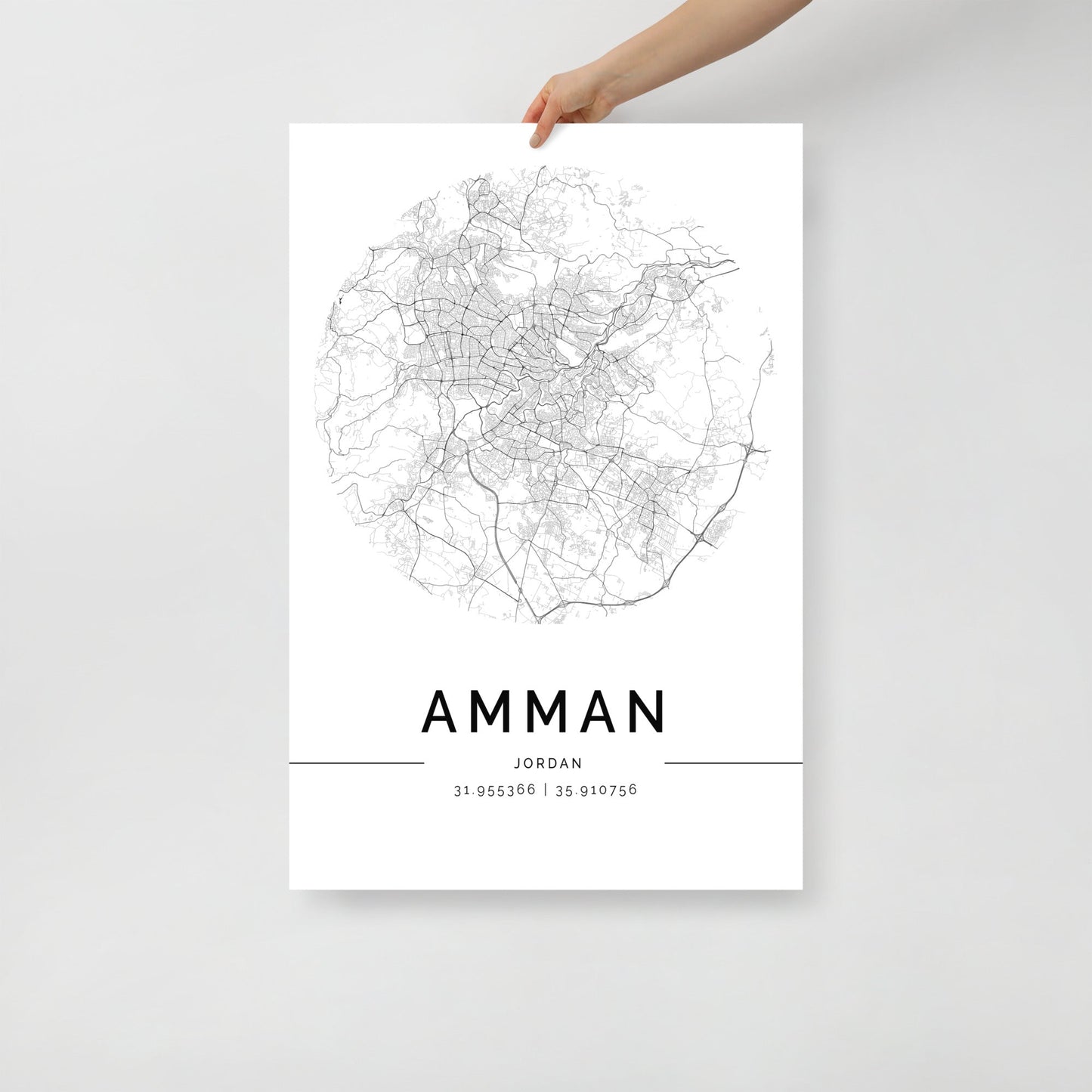 In the image, an elegant piece of wall art from FN Prints is displayed. This Amman City Map boasts a minimalist circular design that intricately outlines the city's streets. Incorporating detailed elements, it beautifully captures the essence of urban landscapes with precise coordinates "31.953566, 35.910756" written beneath. The artwork prominently features "AMMAN, JORDAN" against a clean white background.